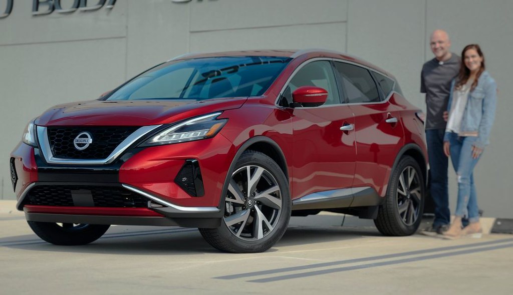Happy Dingman customers standing next to thier red Nissan Murano after repair in Omaha Happy-Dingman-customers-standing-next-to-thier-red-Nissan-Murano-after-repair-in-Omaha